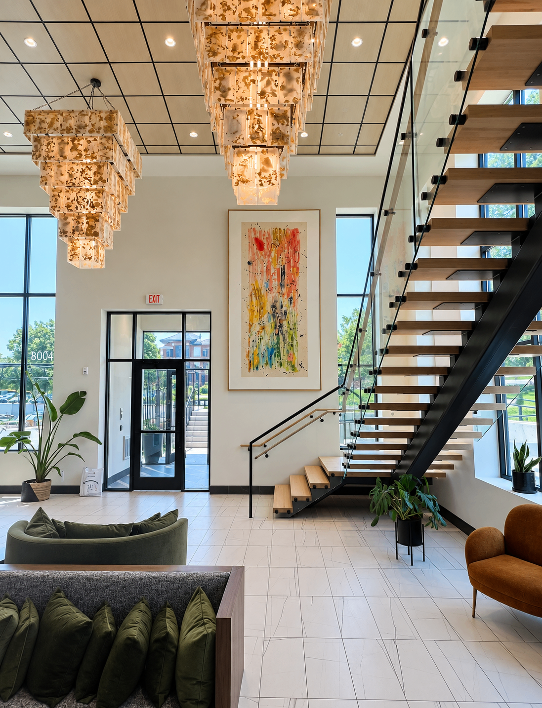 Colorful abstract painting installed in a bright lobby with chandeliers and a floating staircase
