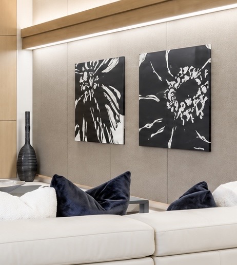 Two black and white abstract botanical paintings installed side by side above a sofa