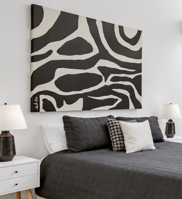 Black and white abstract painting with bold organic flowing forms installed above a bed